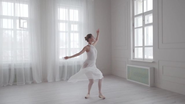 graceful ballerina dancing and tiptoeing in pointe shoes in a bright dance class