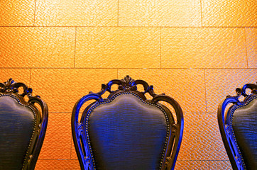 Black chairs in restaurant against golden wall on Celebrity Cruises luxury cruise ship liner