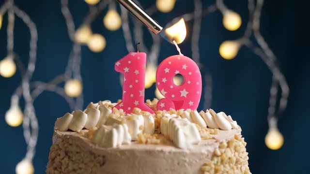 Birthday cake with 19 number pink candle on blue backgraund. Candles are set on fire. Slow motion and close-up view