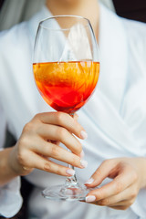 sexy woman holding a glass with aperol cocktail and smiling in the sun