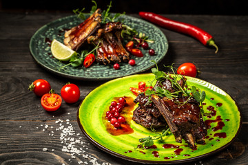 braised ribs with berry sauce on two plates decorated with seedlings of peas, sunflowers, beets