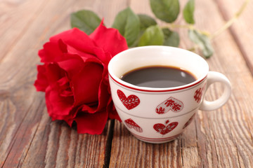 coffee cup and red rose on wood background