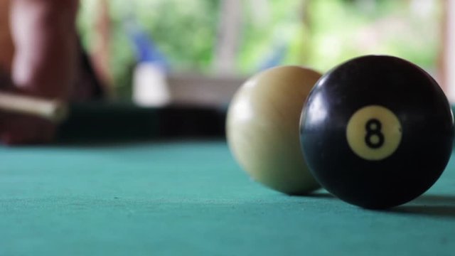 Man plays pool. He hits a white ball against eight ball with focus change. Static, focus movement.