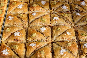 Close up of traditional oriental sweet pastry cookies known as backlava, Turkish desert with sugar, honey, walnuts and pistachio, in display at an weekend street food market, top view, soft focus