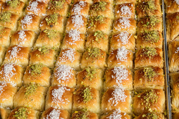 Close up of traditional oriental sweet pastry cookies known as backlava, Turkish desert with sugar, honey, walnuts and pistachio, in display at an weekend street food market, top view, soft focus