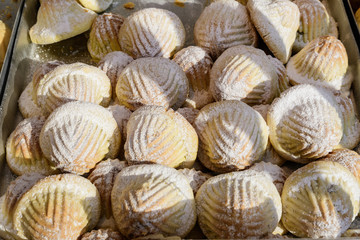 Close up of traditional oriental sweet filled pastry cookies known as mamul or Mamoul, Arab desert with sugar,  walnuts and dates, in display at an weekend street food market, top view, soft focus