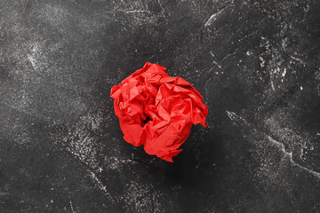 Red crumpled paper ball on a dark background. Idea concept.