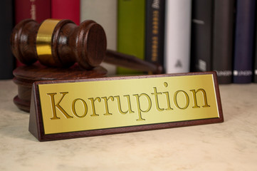 Golden sign with engraved german word for corruption - korruption on a desk