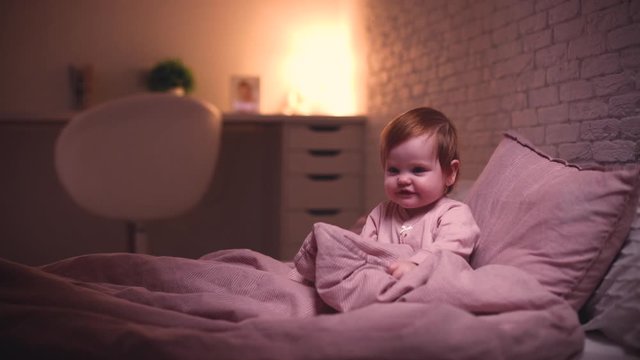 adorable little baby girl playing hide and seek in bed before going to sleep