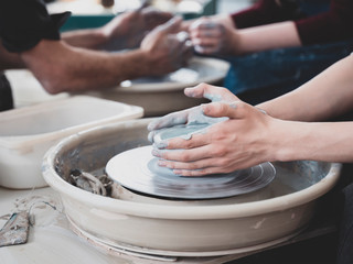 Guy throw a pot craftsman teaching how to molding clay vessel on pottery wheel crafts workshop