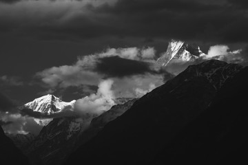 Black and white landscape of dark clouds swirling around the Machapuchare aka the Fishtail Mountain on the Annapurna Base Camp trekking trail in the Nepal Himalaya.
