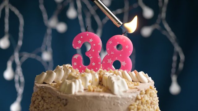 Birthday cake with 38 number pink candle on blue backgraund. Candles are set on fire. Slow motion and close-up view