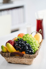 basket with fresh fruit and juice on white modern office table