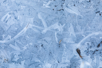 The macro or closeup shot of ice texture or background on the puddle or pool in the frost winter weather