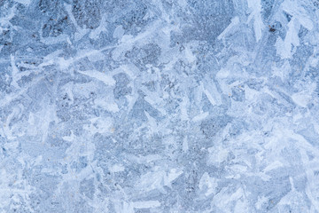 The macro or closeup shot of ice texture or background on the puddle or pool in the frost winter weather
