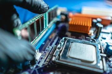 Engineer repairman holding hands RAM memory to insert into the socket of the motherboard....