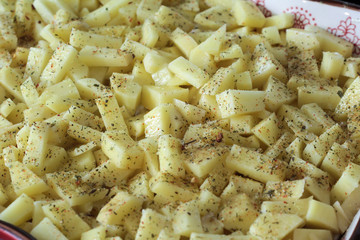 Raw potatoes with spices cubes before baking