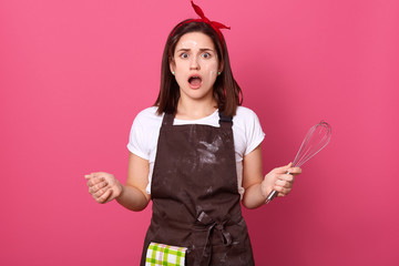 Housewife female cook baker dresses brown apron, white t shirt and red head band posing isolated...