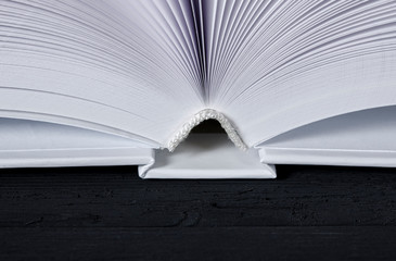 The white-cover book is on a textured wooden table.