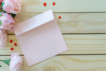 close up top view on pink color letter with mini heart and group of pastel roses over wood plank table background for mother's day and valentine day design concept	