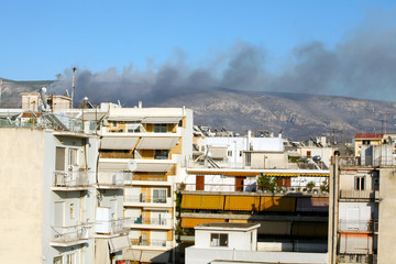 Fototapeta premium houses in athens with smoke of fire in backround
