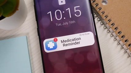 Smartphone showing a medical notification banner appearing on the lock screen. Mobile phone warning that it is time to take the medication for the day.