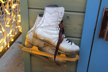 old white unused dirty painted skates made of cracked leather, hanging on the wall