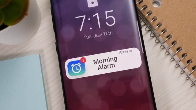 A smartphone showing a morning clock alarm notification on the lock screen.