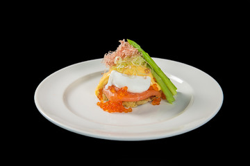 Delicious breakfast with Eggs Benedict and salmon caviar (Ikura) on the black background