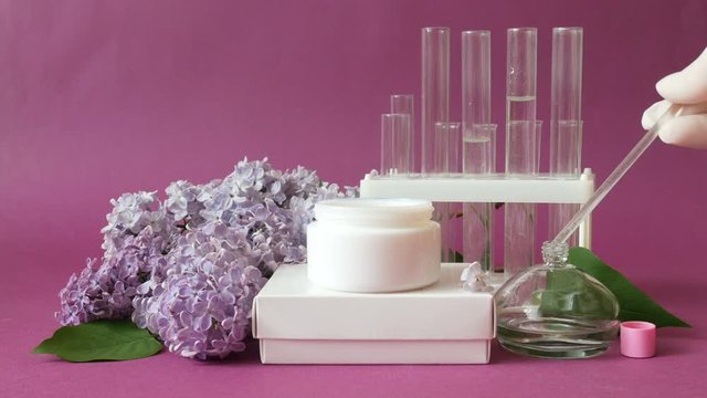 natural cream cosmetic production, organic oils, lilac flowers, stand with chemical tubes, handmade cosmetic concept 