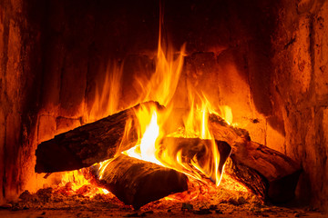 Fire in a fireplace with logs and flames creating a sense of warmth and coziness. - obrazy, fototapety, plakaty
