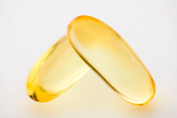 Omega 3 fish oil, two gel capsules macro photo over white background, food supplement for health care. Pharmaceutical industry. Pharmacy.