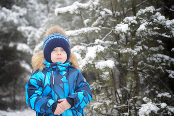 Fototapeta na wymiar Boy in warm clothes in the winter forest