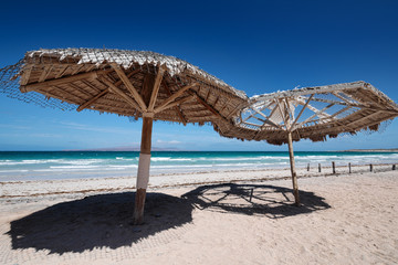 Large wooden umbrellas at sandy tropical beach