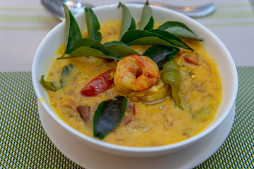Seafood curry being served with shrimp on top