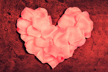 Heart made of rose textile petals on grunge red  background