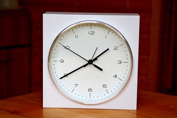 White bracket clock, clock on a table, on a wooden table 