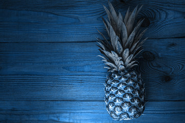 Blue pineapple on wooden background flatlay. Color trends 2020, tropical fruits, diet, slimming...