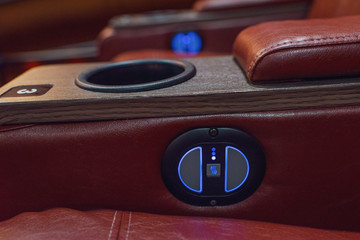 The controls on a luxurious reclining leather chair in a recently renovated movie theater