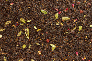 texture background of loose Ceylon leaf black tea with herbs and berries top view