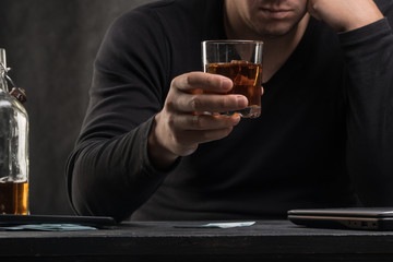 Alcoholic addict. Man near the table with alcohol and a glass. Dangerous habit. Unhealthy life concept. Social problem.
