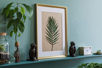 Interior design of living room with gold mock up photo frame on the green shelf with beautiful plants in different hipster and design pots. Elegant personal accessories. Home jungle. Template. 