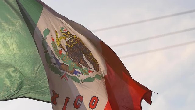 Mexican Flag flowing in the sunshine. Slow-motion it blows around in the sky. Sun shines through the green white and red flag.