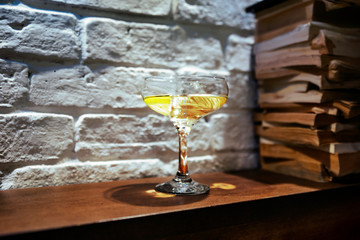 Glass with martini and yellow lemon in a brutal interior, still life.
