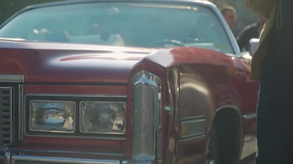 People viewing classic red convertible car at Romanian motor show, close up