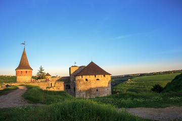 Naklejka na ściany i meble Summer landscape with old antique stone fortress Kamianets-Podilskyi at sunset, Ukraine
