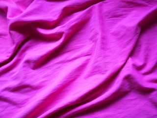 OLYThe surface of the fabric is dark pink. Close-up fragment of crumpled pink polyester fabric.