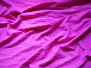 OLYThe surface of the fabric is dark pink. Close-up fragment of crumpled pink polyester fabric.