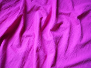 OLYThe surface of the fabric is dark pink. Close-up fragment of crumpled pink polyester fabric.