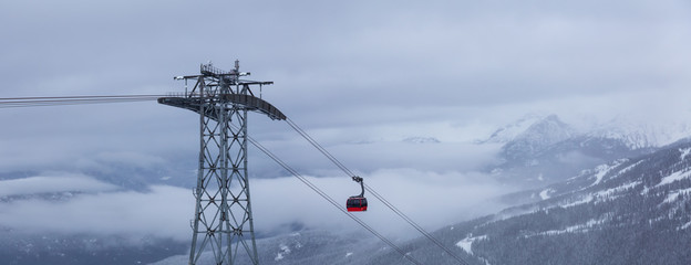 Whistler, British Columbia, Canada. Beautiful View of Peak to Peak Gondola with the Canadian Snow Covered Mountain Landscape during a cloudy and foggy winter day. © edb3_16